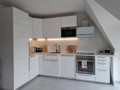 a white kitchen with white cabinets and appliances at LIVORA Altstadt Wilhelmshaven - Stilvoll - Zentrumsnah - TV-Streaming - Balkon - Nordsee - Badewanne in Wilhelmshaven