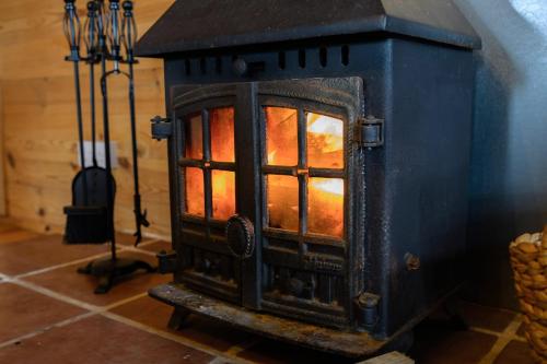 a black stove with a fire inside of it at Reindeer Lodge Very Special Retreat With Private Hot Tub Near Cannock Chase By StayStaycations in Colton