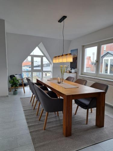 a dining room with a wooden table and chairs at LIVORA Altstadt Wilhelmshaven - Stilvoll - Zentrumsnah - TV-Streaming - Balkon - Nordsee - Badewanne in Wilhelmshaven