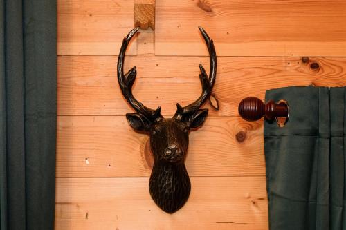 a deer head with horns hanging on a wall at Reindeer Lodge Very Special Retreat With Private Hot Tub Near Cannock Chase By StayStaycations in Colton