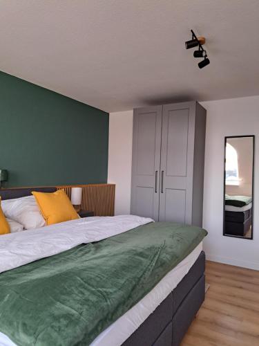 a bedroom with two beds and a green wall at LIVORA Altstadt Wilhelmshaven - Stilvoll - Zentrumsnah - TV-Streaming - Balkon - Nordsee - Badewanne in Wilhelmshaven