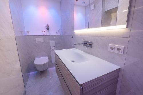 Baño blanco con lavabo y aseo en TANIC Deluxe Apartment Garden Central Industrial Fair en Düsseldorf