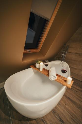 a bathroom with a bath tub with two glasses of wine at The Cozy Chalet in Bosanski Petrovac