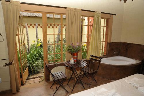 a bedroom with a tub and a table and chairs at African Silhouette Guesthouse in Benoni