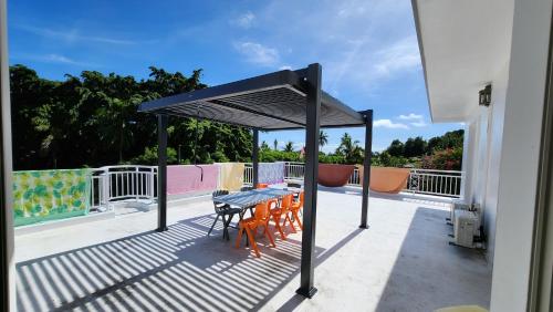 a black canopy on a deck with a table and chairs at La Maison Orange in Moorea