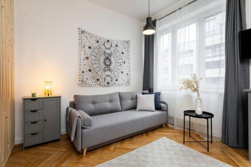 ein Wohnzimmer mit einem grauen Sofa und einem Fenster in der Unterkunft Moonlight Studio Stary Mokotow in Warschau