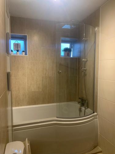 y baño con ducha y bañera con puerta de cristal. en Modern Spacious 2 Bed Apartment **Free WIFI & Parking** en Goodmayes