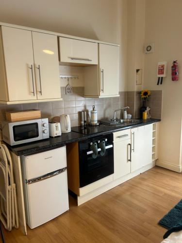 a kitchen with white cabinets and a stove top oven at Comfy studio in London