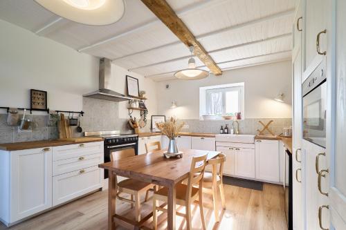 une cuisine avec des armoires blanches et une table en bois dans l'établissement Le Moulin Saint-Nicolas, à Maizy