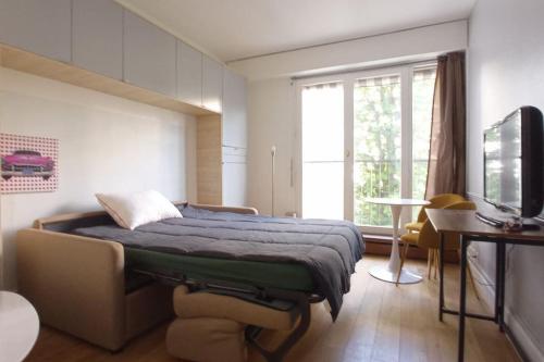 a bedroom with a bed and a tv and a window at Jardin du Ranelagh in Paris