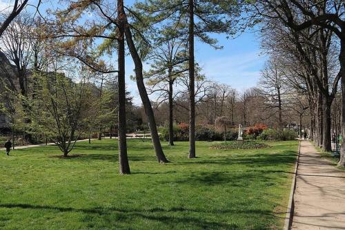 a park with green grass and trees and a sidewalk at Jardin du Ranelagh in Paris