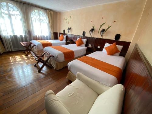 a hotel room with three beds and a couch at Kitu Hotel in Quito