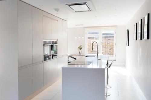 a white kitchen with white cabinets and a counter at Luxurious Central Windsor Town House in Windsor