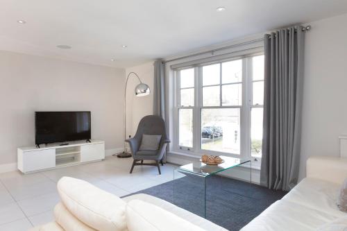 a living room with a white couch and a tv at Luxurious Central Windsor Town House in Windsor