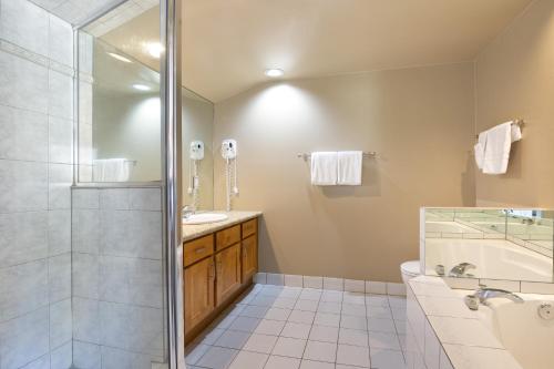 a bathroom with a shower and a sink and a tub at Powder's Edge by LaTour Hotels and Resorts in Whistler