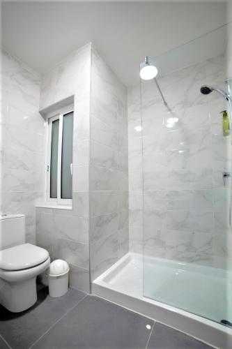 a white bathroom with a toilet and a shower at Elise Apartments in Il-Gżira