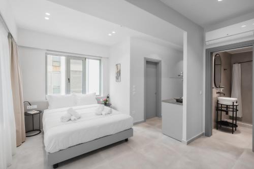 a white bedroom with a bed with two stuffed animals on it at ELA FIVE RESIDENCES in Athens