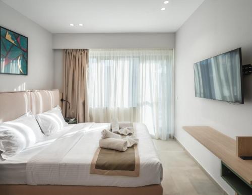 a bedroom with a large white bed with a television on the wall at ELA FIVE RESIDENCES in Athens