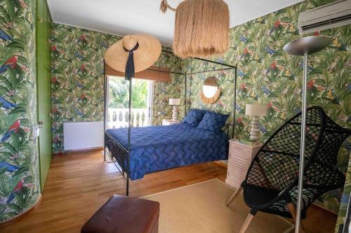 Schlafzimmer mit einem Bett mit blauer Bettwäsche und tropischen Tapeten in der Unterkunft Dreamy relaxing secluded Villa Aurora in Palaia Fokaia