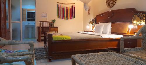 a bedroom with a large wooden bed and a chair at Aivilo Home in Kampala