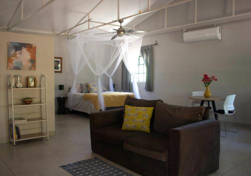 a living room with a couch and a bed at Acacia Cottage in Maun