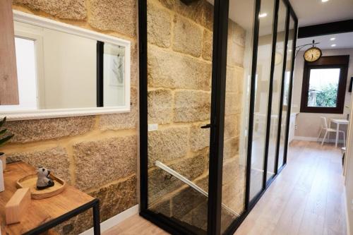 Cette chambre est dotée d'un mur en pierre et d'une porte en verre. dans l'établissement Villa Julia, à Ribadavia