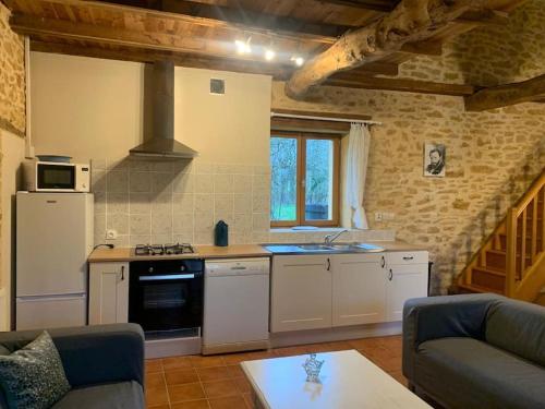 a kitchen with a stove top oven next to a couch at Gite de la Renardière in Paunat