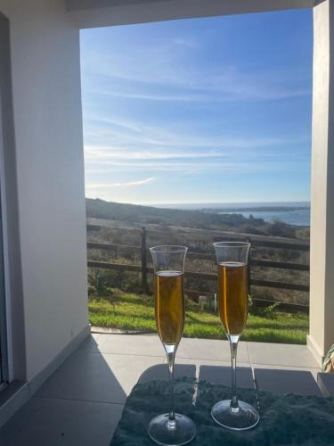 two champagne glasses sitting on a table in front of a window at De Santa Villas in St Helena Bay