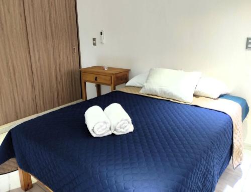 een slaapkamer met een blauw bed en handdoeken bij Departamento Puerta Dorada in Manzanillo