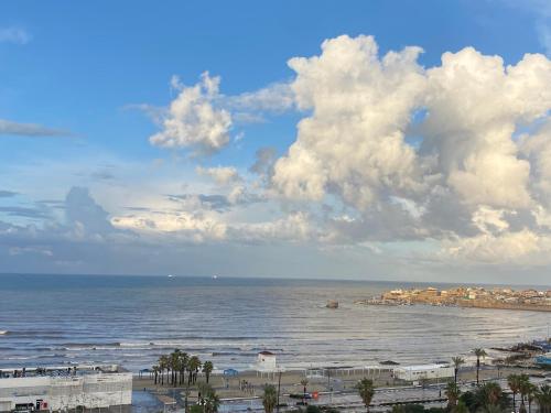 a view of a beach with clouds and the ocean at Acre sea view 11th floor apartment in ‘Akko