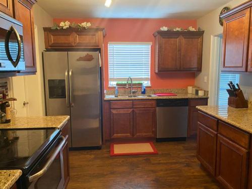 a kitchen with wooden cabinets and a stainless steel refrigerator at Chic 3BR Home w/ Big Yard in Winter Park-Orlando in Orlando