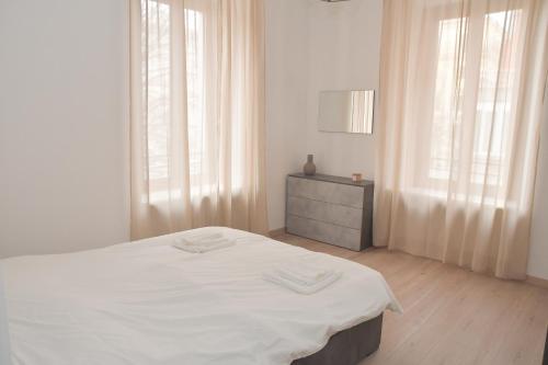 a white bedroom with a bed and a dresser at Casa Ambra in Ancona