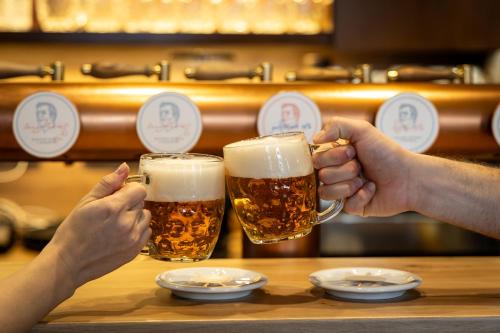 two people holding up glasses of beer at Hotel Slunce in Rýmařov