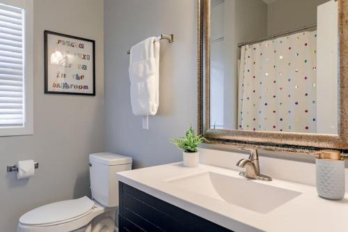 a bathroom with a sink and a toilet and a mirror at UNL Retreat Eclectic 5bd 5mins to Downtown in Lincoln
