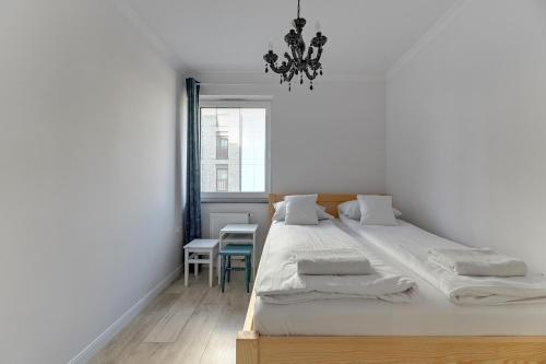 um quarto com uma cama, uma mesa e um lustre em Grobla Centrum 2 by Grand Apartments em Gdansk