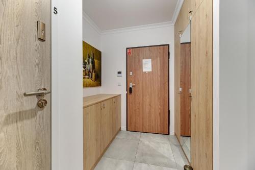 um corredor com portas de madeira num quarto em Grobla Centrum 2 by Grand Apartments em Gdansk