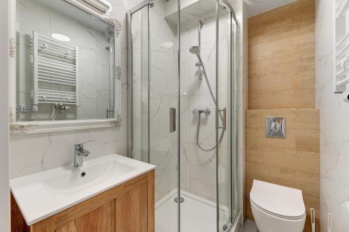 uma casa de banho com um chuveiro, um lavatório e um WC. em Grobla Centrum 2 by Grand Apartments em Gdansk