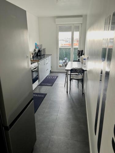 une cuisine avec un réfrigérateur en acier inoxydable et une table dans l'établissement Village olympique, à Saint-Denis