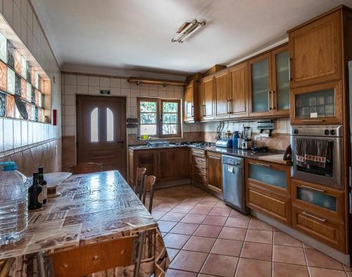 a large kitchen with wooden cabinets and a table at Aldeia Caiçara Surf House in Sagres