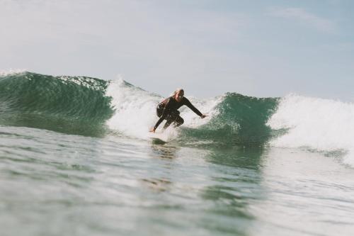 a man riding a wave on a surfboard in the ocean at Aldeia Caiçara Surf House in Sagres