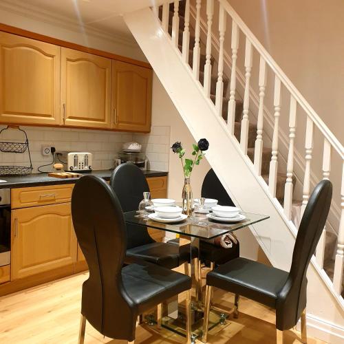 een eetkamer met een tafel en stoelen en een trap bij Carter House in Bradshaw