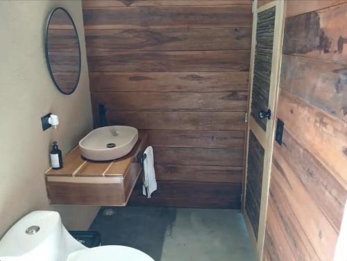 La salle de bains est pourvue d'un mur en bois et de toilettes. dans l'établissement Cabaña Vista al Mar Tayrona, A/C, à Los Naranjos