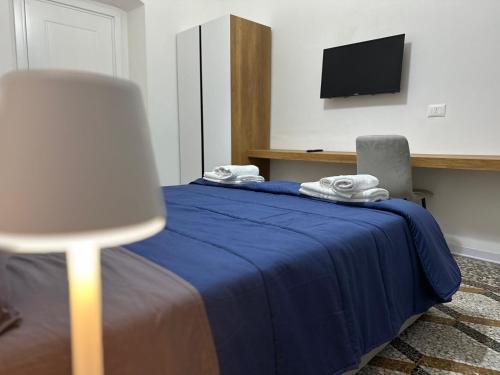 ein Schlafzimmer mit einem blauen Bett, einem Stuhl und einem Fernseher in der Unterkunft Mosaic Inn in Genua