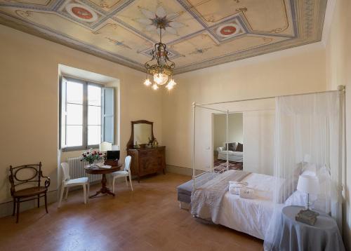 a bedroom with a bed and a table and a chandelier at B&B Palazzo Mattei in Novafeltria