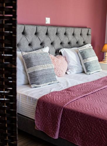 a bedroom with a large bed with pink walls at Nikitas Apartments & Suites in Kanali