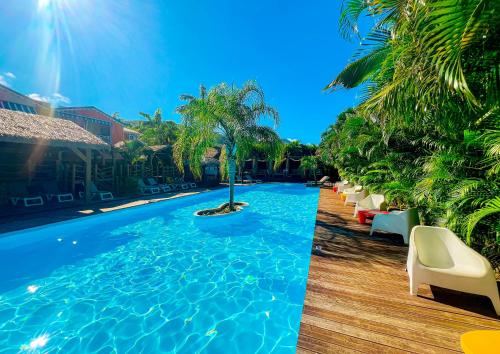 una piscina con palmeras y tumbonas en Tropicana Suites en Deshaies