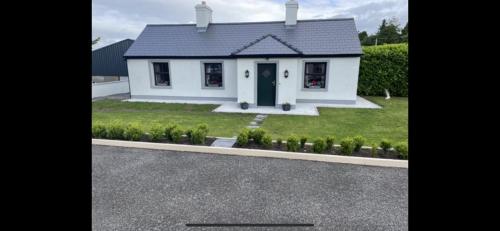 a white house with a blue door in a yard at Kate’s Cottage in Westport