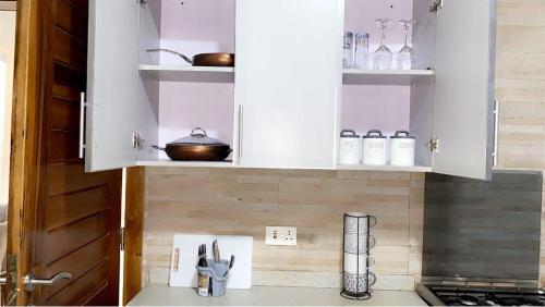 una cocina con armarios blancos y algunos utensilios. en Ayan Villas en Accra