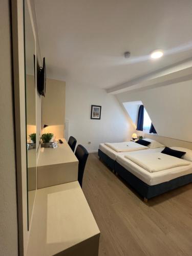 a bedroom with two beds and a desk in it at Hotel Pelikan in Kitzingen