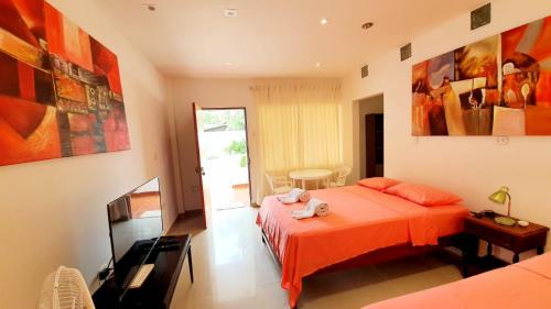 - une chambre avec un lit orange et une télévision dans l'établissement Edelmon't Beach, à Organos